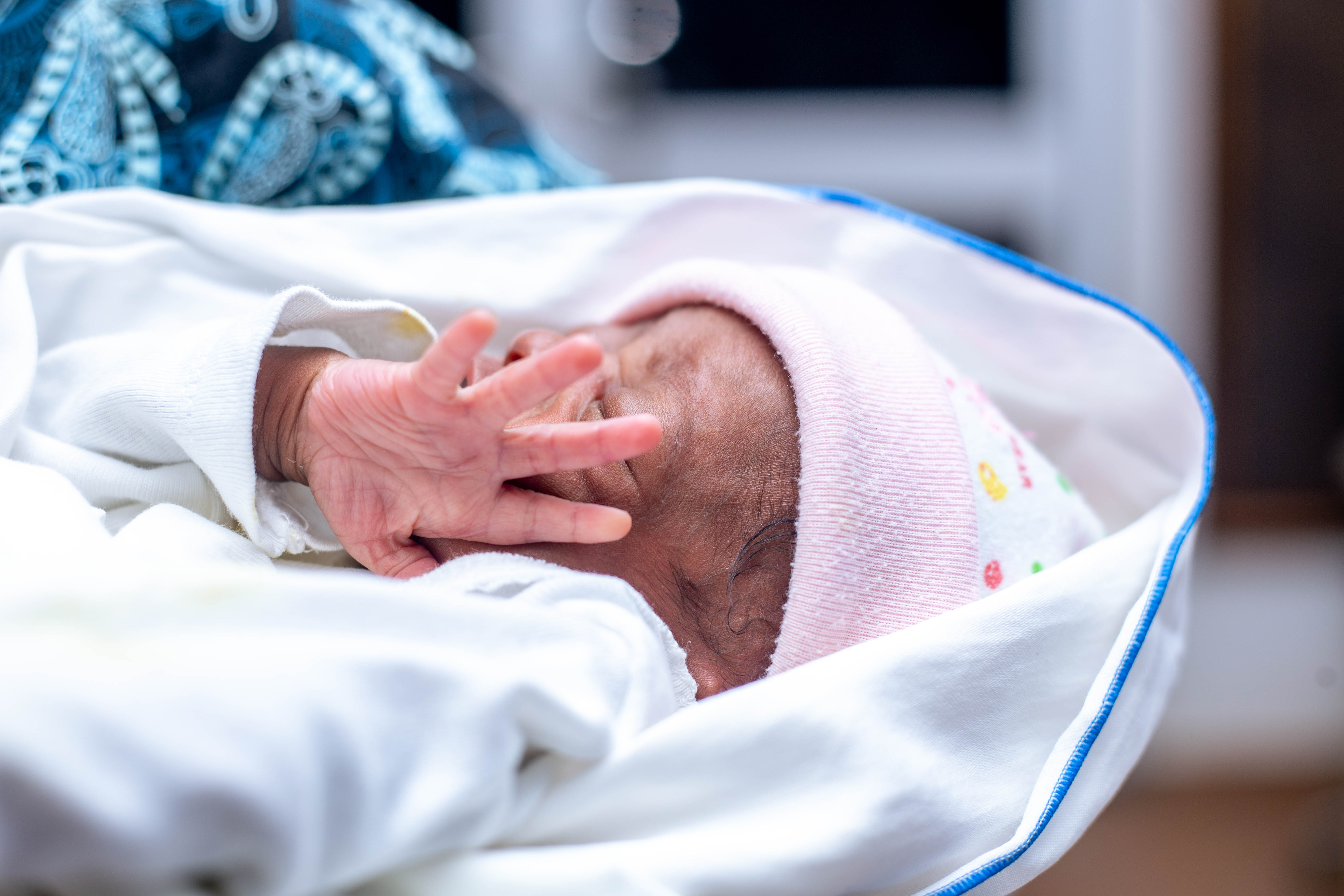 A newborn wrapped in a Purple Basket blanket